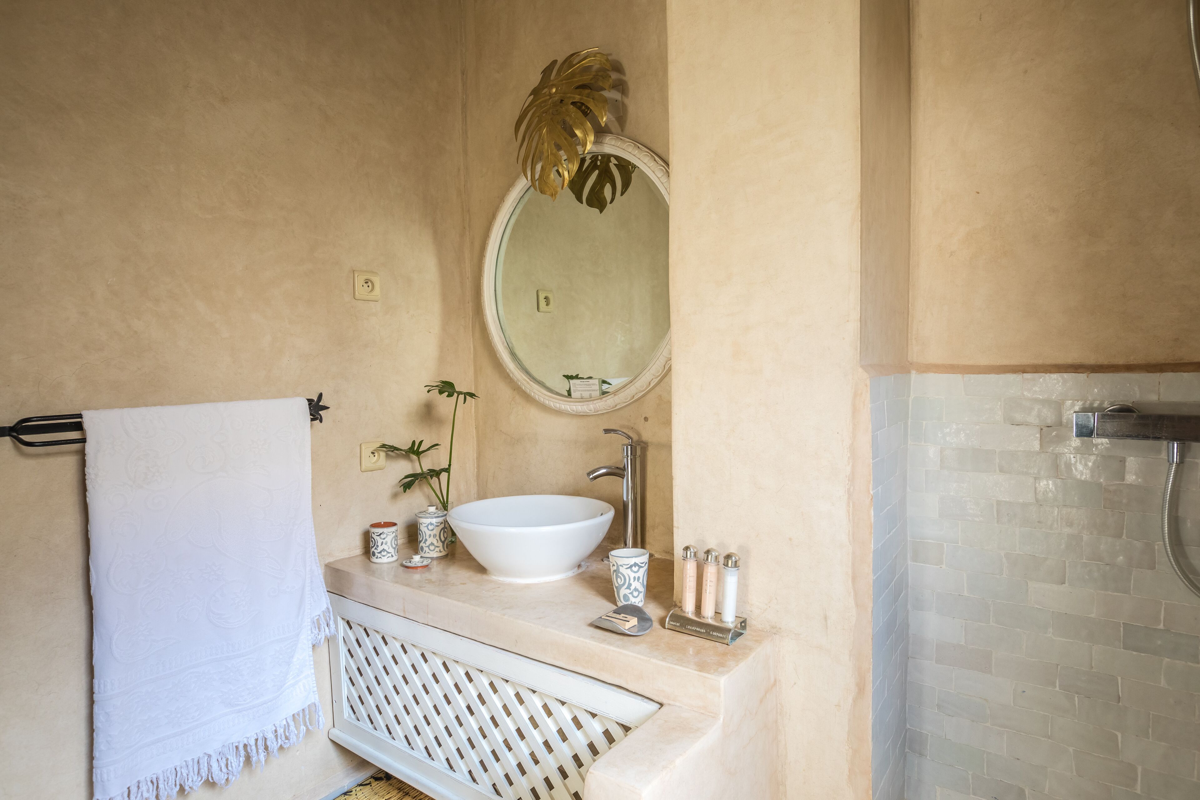A bathroom with a white sink, a round mirror, and a towel rack.