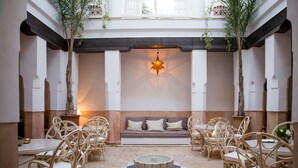 A courtyard with a central seating area, surrounded by tables and chairs, and a decorative fountain. - Riad Olema et Spa (Marrakech)