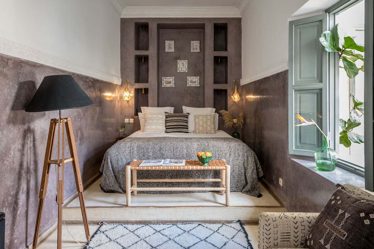 Un dormitorio con cama, mesita de noche, lámpara y adornos en la pared.