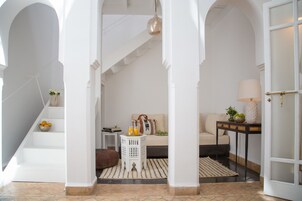 Un vestíbulo espacioso con paredes blancas, una escalera, un sofá y una mesa con lámpara.