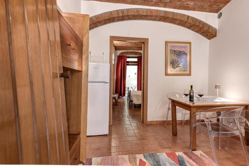 Eine Küche mit Kühlschrank, einem Esstisch mit Stühlen und einem Bild an der Wand.