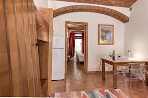 A kitchen with a refrigerator, a dining table with chairs, and a painting on the wall. - Scarlino Ospitalità Diffusa (Scarlino)