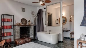Ein Badezimmer mit freistehender Badewanne, einem Spiegel und einer Dusche.
