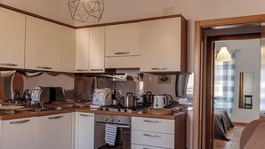 Eine kompakte Küche mit modernen Geräten, inklusive Backofen, sowie ein Essbereich mit einer Couch und einem Tisch.