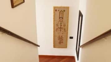 Un escalier avec des marches en bois et des rampes noires, menant à une porte ornée d’un panneau décoratif.