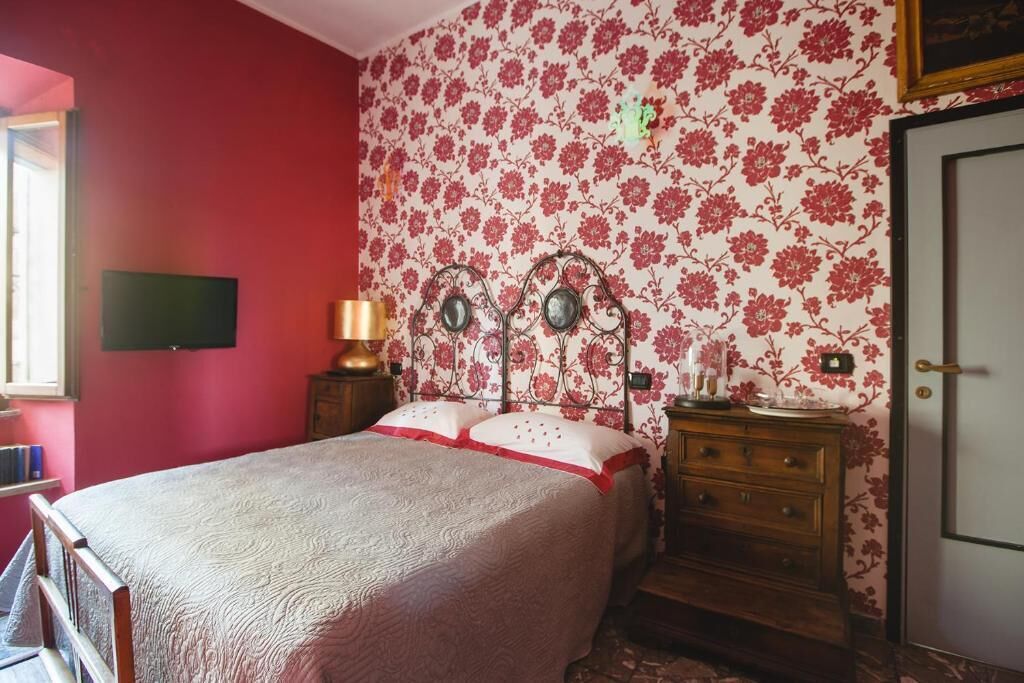 A bedroom with a bed, a dresser, a mirror, and a television on the wall.