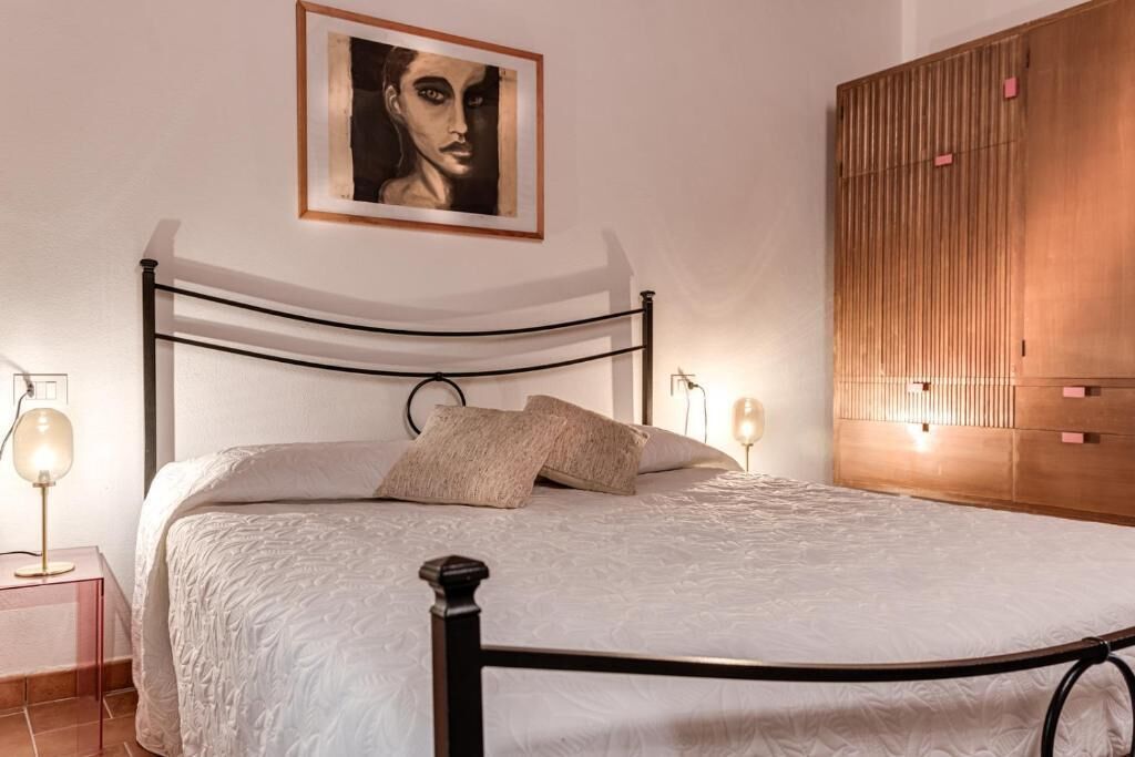 Ein Bett mit Metallgestell, eine Nachttischlampe und eine Wandleuchte.
