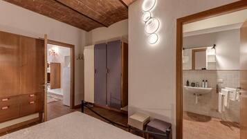 Una habitación de hotel con una cama, un armario de madera, un espejo y un baño con lavabo y toallero.
