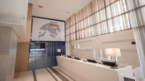 A modern reception area with a large welcome sign, a reception desk, and a patterned wall.