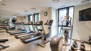 A gym with treadmills, elliptical machines, and dumbbells.