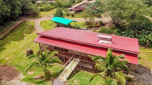 A two-story building with a red roof, surrounded by lush greenery and palm trees. - Hotel del Bosque (Santa Rita)