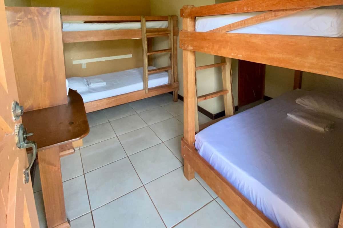 Una habitación con literas, un pequeño escritorio de madera y una lámpara en el techo.
