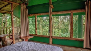 A room with a bed, a table, and a view of the forest. - Hotel del Bosque (Santa Rita)