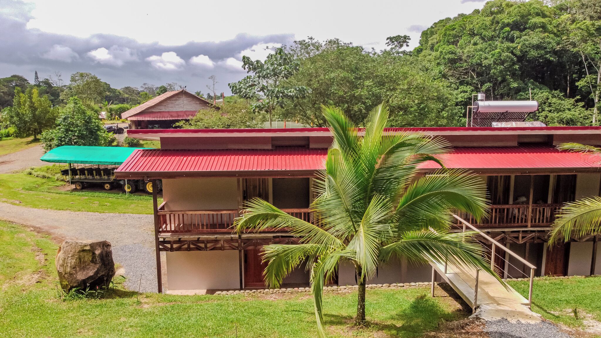A two-story building with a red roof, a balcony, and a staircase leading to the upper floor.