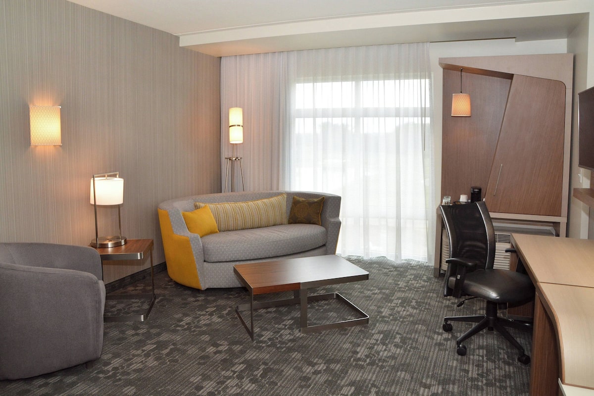 Ein Hotelzimmer mit Sofa, Sessel, Schreibtisch und Stuhl.