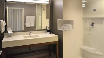 Une salle de bain moderne avec un grand miroir, un lavabo, une douche et un porte-serviettes.
