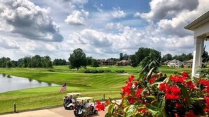 A golf course with a pond, American flag, and golf carts. - Courtyard by Marriott Youngstown Canfield (Canfield)