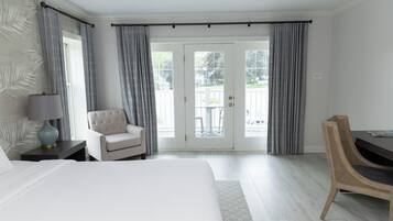 Habitación de hotel con cama, una silla, un escritorio y vistas al exterior a través de un ventanal.
