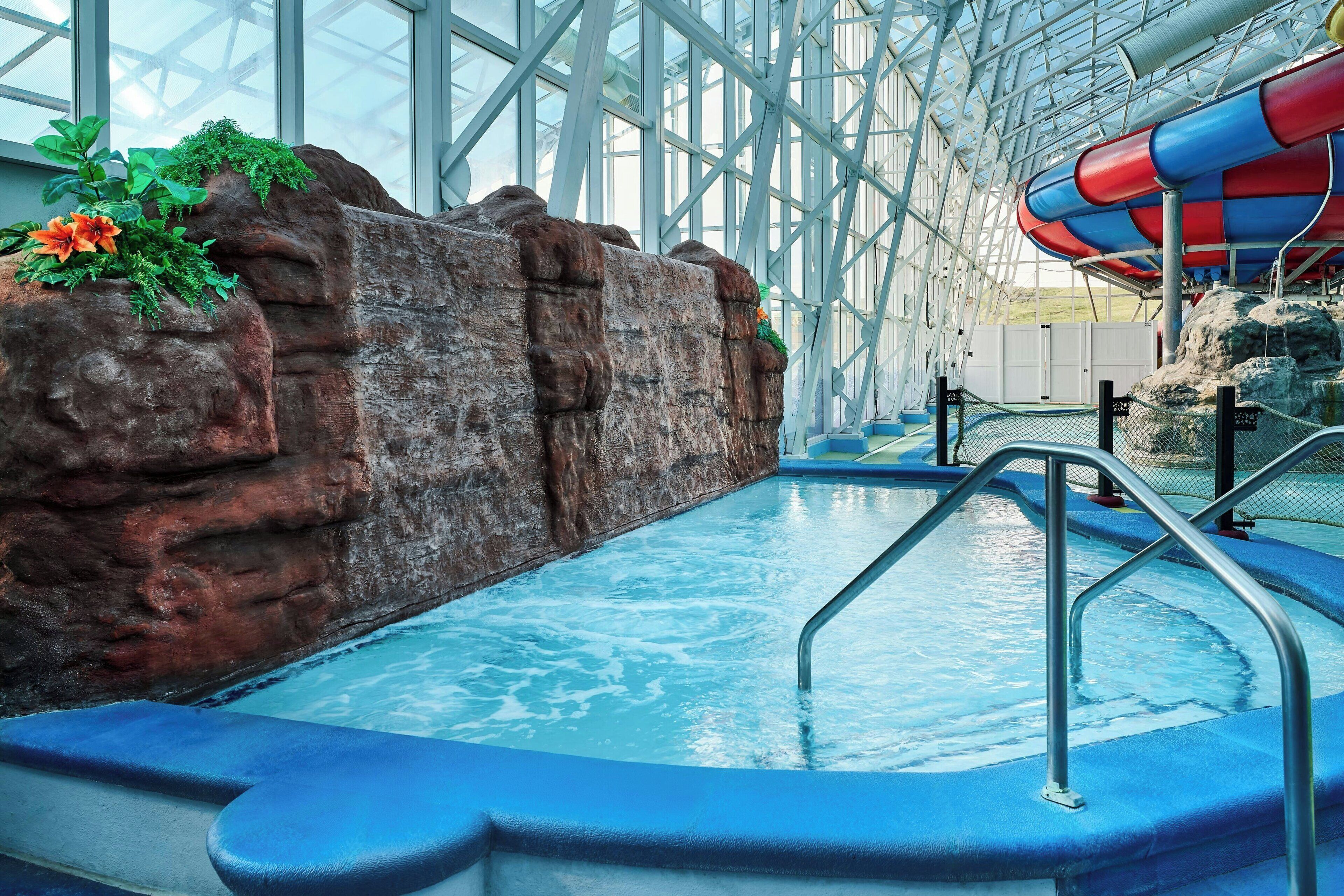 An indoor water park with a pool, rock formations, and a water slide.