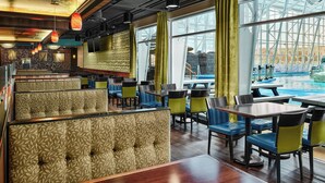 A restaurant with a pool view, featuring booths and tables with chairs, and a bar area with a patterned wall. - Residence Inn Rapid City (Rapid City)