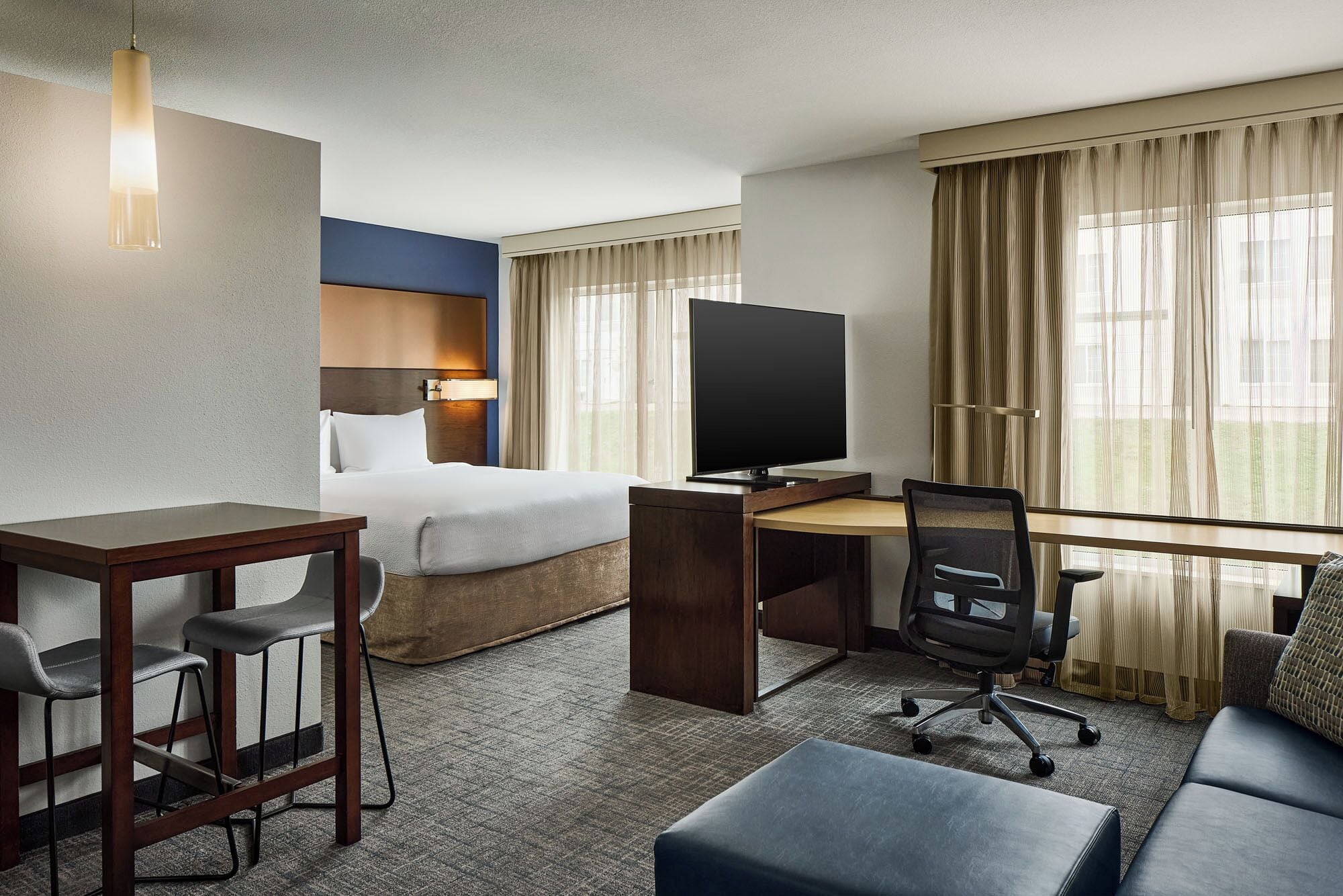 Een hotelkamer met een bed, een bureau met een computer, een televisie, een bank en een stoel.