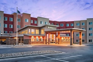A multi-story hotel with a covered entrance, stone pillars, and a flag. - Residence Inn Rapid City (Rapid City)