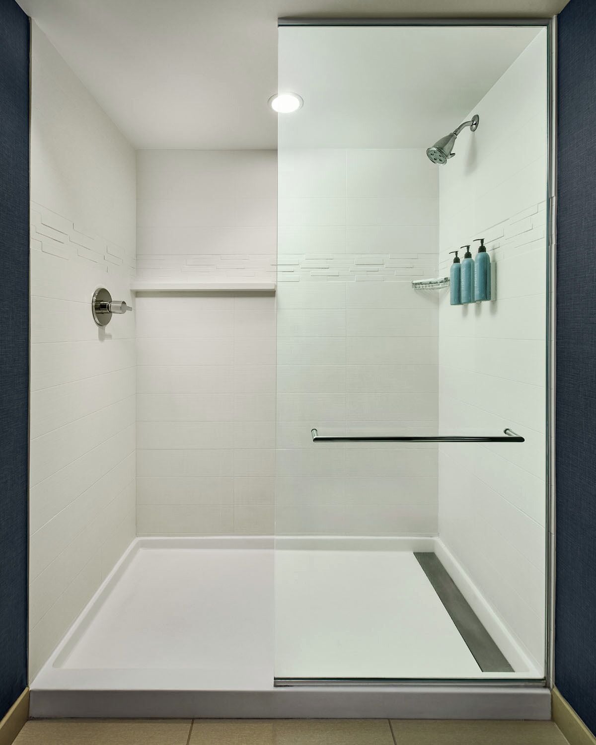 Une douche moderne dotée d’une porte en verre, d’un pommeau de douche à main et d’un porte-serviettes.