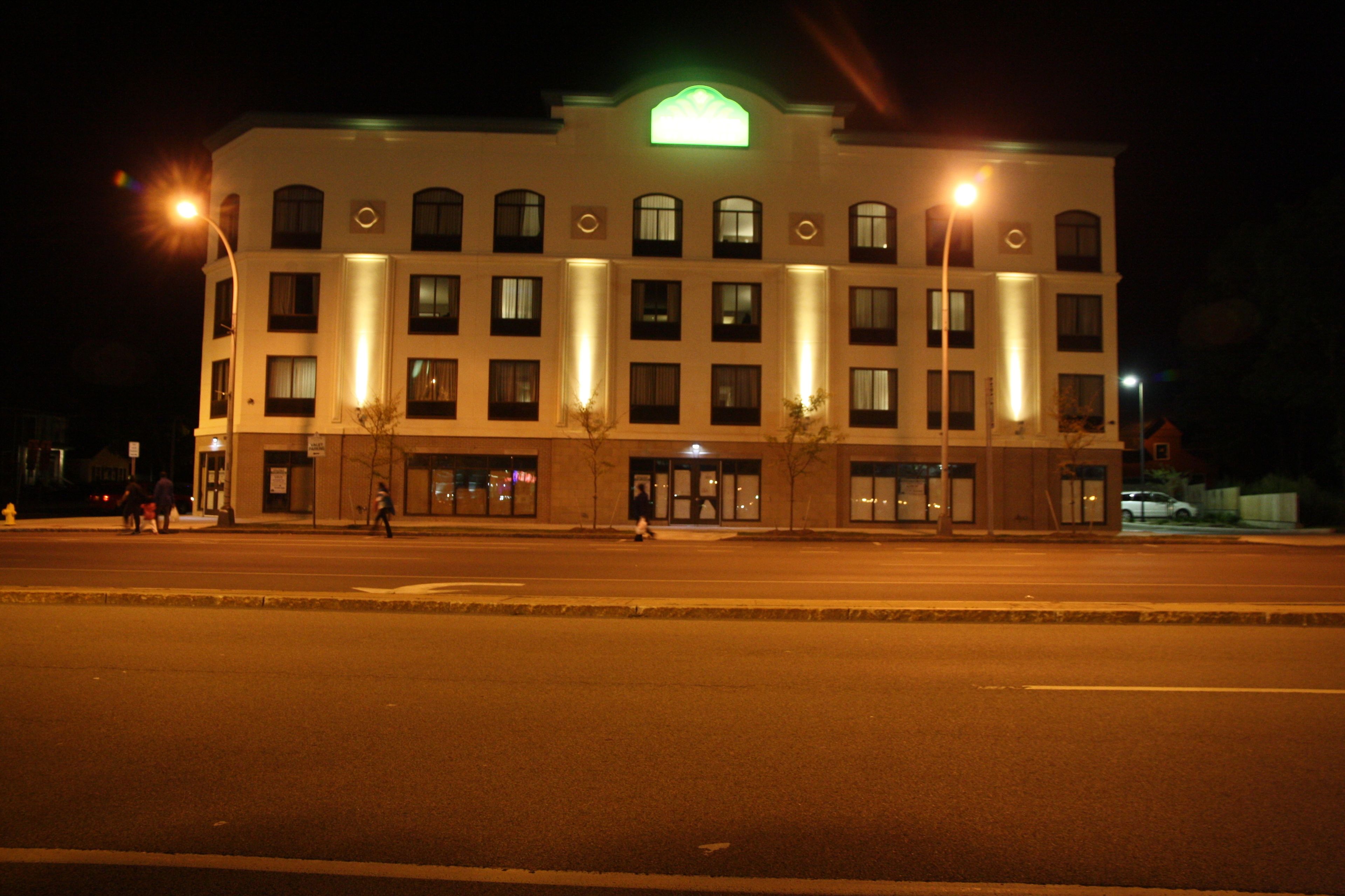 A multi-story hotel with a central entrance, evenly spaced windows, and a green sign above the entrance.
