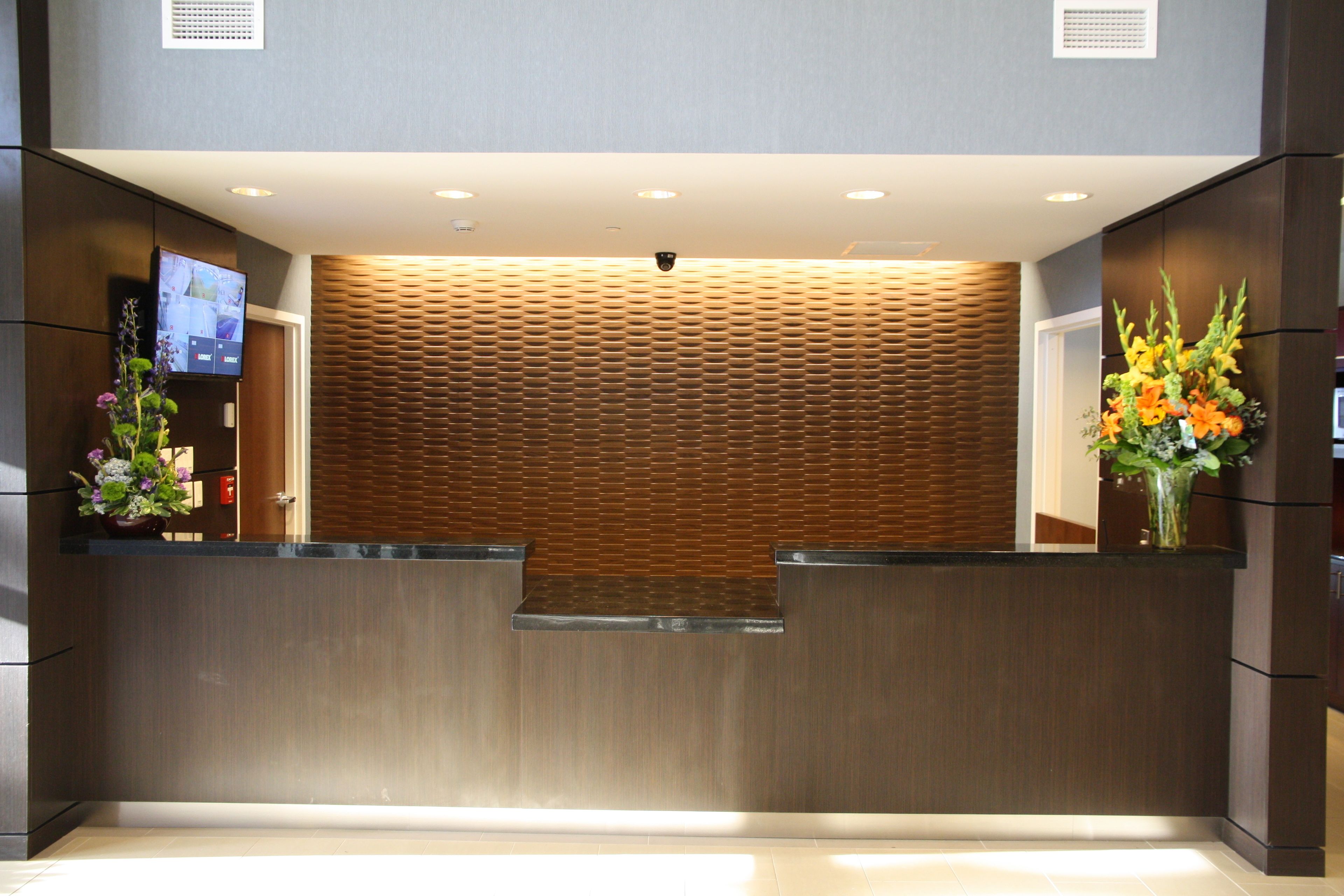 A reception area with a wooden panel wall, a flat-screen TV, and a flower arrangement.