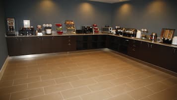 A kitchen with dark cabinets, a tiled floor, and various appliances like a microwave and coffee maker.