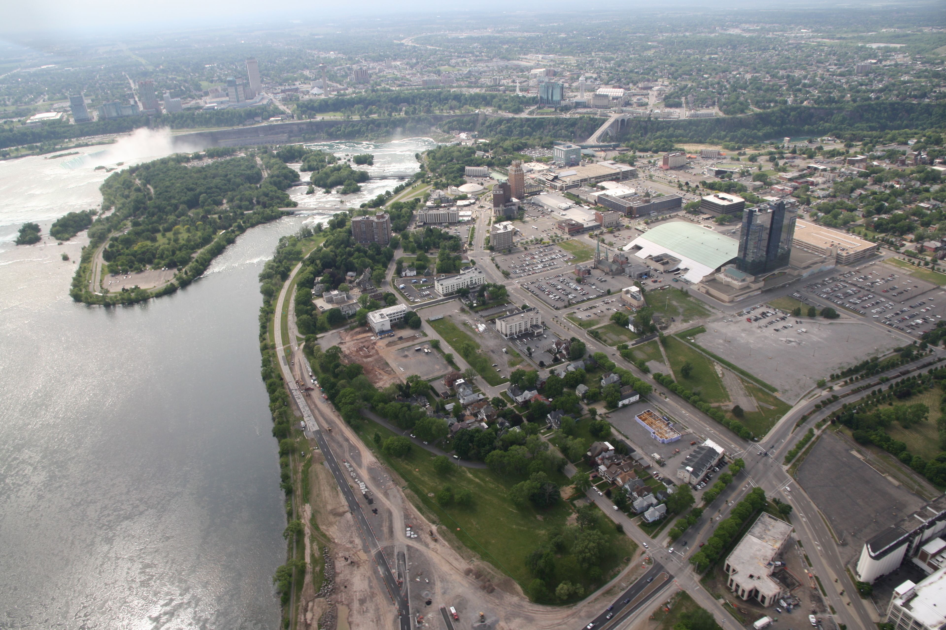An aerial view of a city with a river, buildings, and roads.
