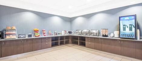 A breakfast area with a self-service station, microwave, coffee machine, and a refrigerator.
