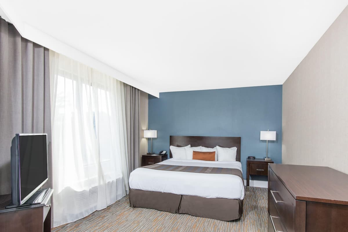 A hotel room with a bed, a TV, a desk, and a lamp.
