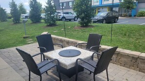 An outdoor patio with a square table and four chairs, surrounded by a low stone wall and a grassy area. - Candlewood Suites Smyrna - Nashville by IHG (Smyrna)