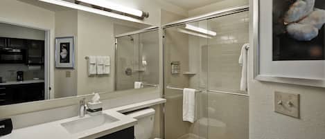 A modern bathroom with a glass-enclosed shower, a white sink, and a toilet.