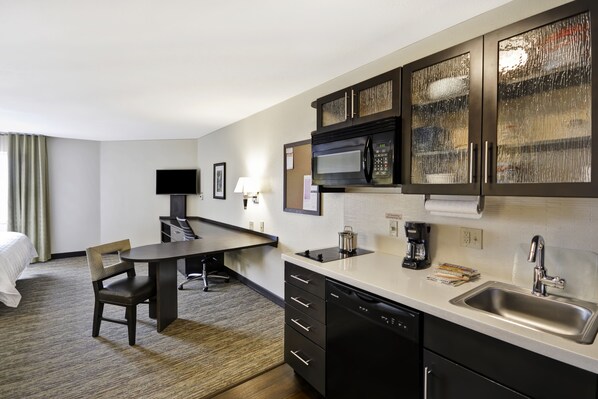 Quarto de hotel compacto com cozinha compacta, área de refeições, cama e televisão.