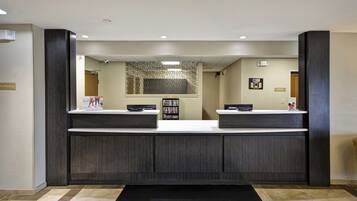 A reception area with a dark wood reception desk, a security camera, and a 'No Smoking' sign.
