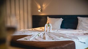 Een opgemaakt bed met witte lakens, een houten hoofdbord en een wandlamp.