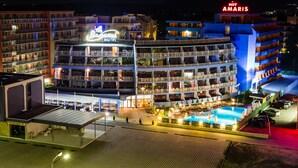 Een meerlaags hotel met balkons, een zwembad en een overdekt buitengedeelte.