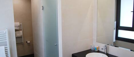 A modern bathroom with a white sink, a large mirror, and a glass shower door.