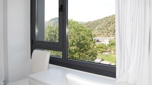 Een kamer met een groot raam, een witte stoel en een witte tafel.