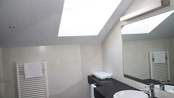 Une salle de bain moderne avec un puits de lumière, un lavabo blanc et un grand miroir.