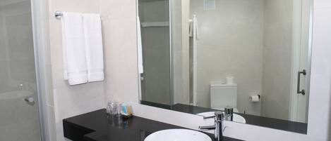 Un baño moderno con encimera negra, lavabo blanco y un espejo grande.