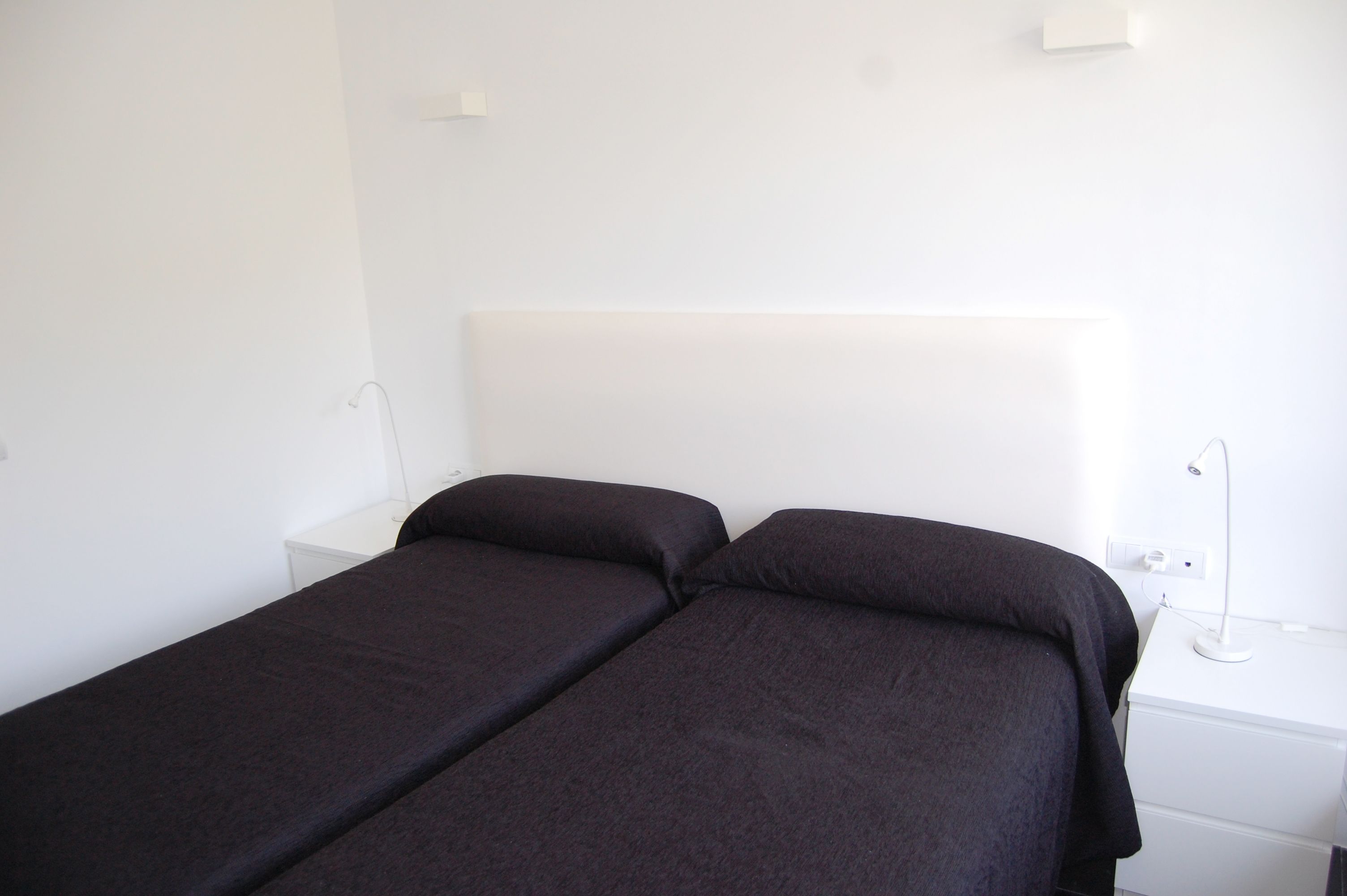 Una cama con dos plazas y un cabecero blanco en una habitación de hotel.