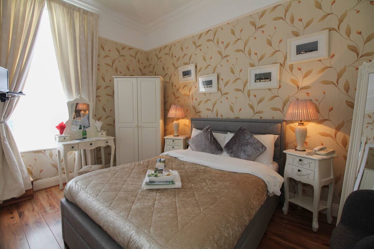 A neatly arranged hotel room with a bed, bedside tables, lamps, and a wardrobe.
