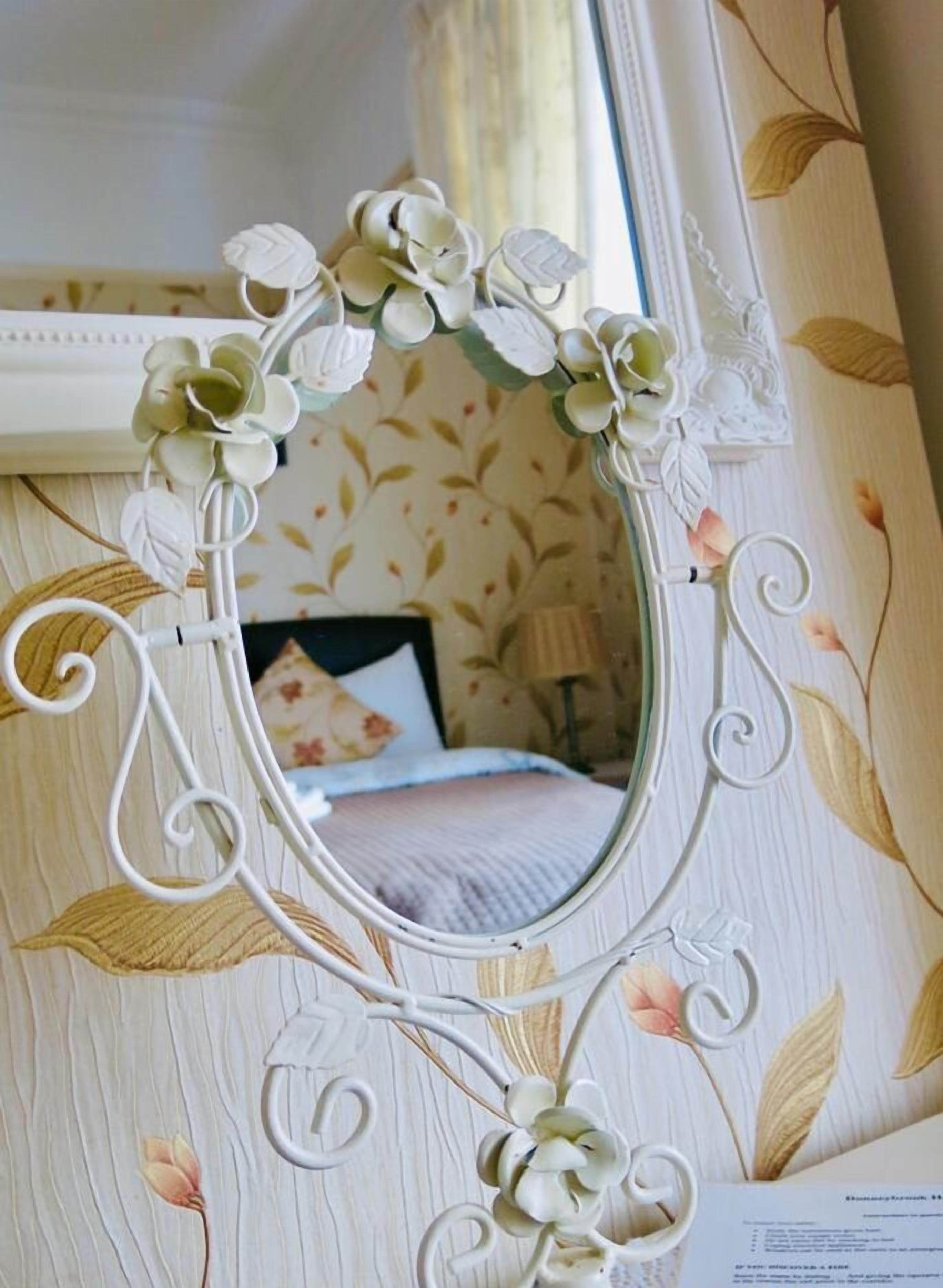 Un espejo con marco floral en una habitación con papel tapiz de motivos florales.