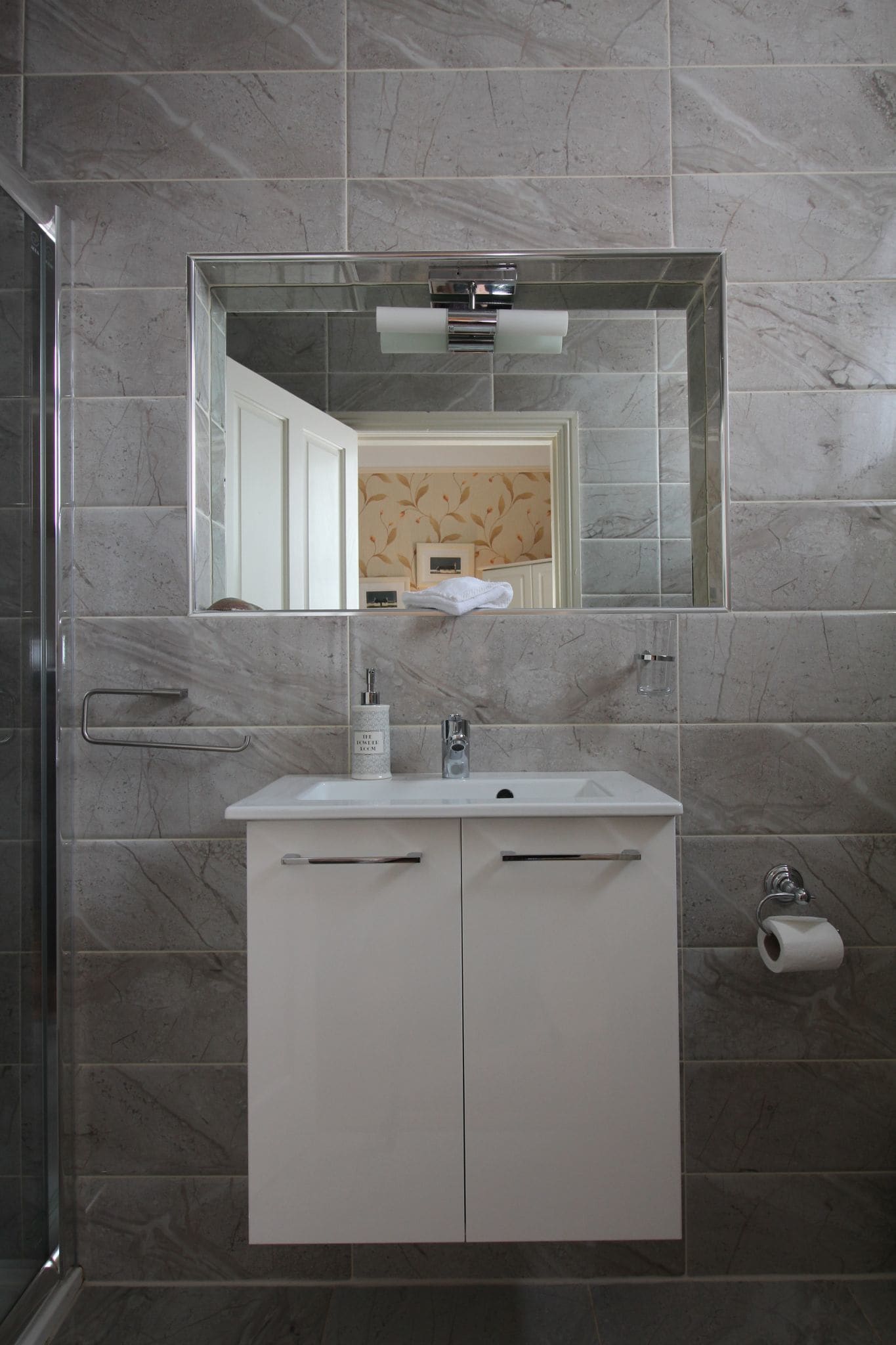 Une salle de bain avec un meuble-lavabo blanc, un miroir et un espace douche.