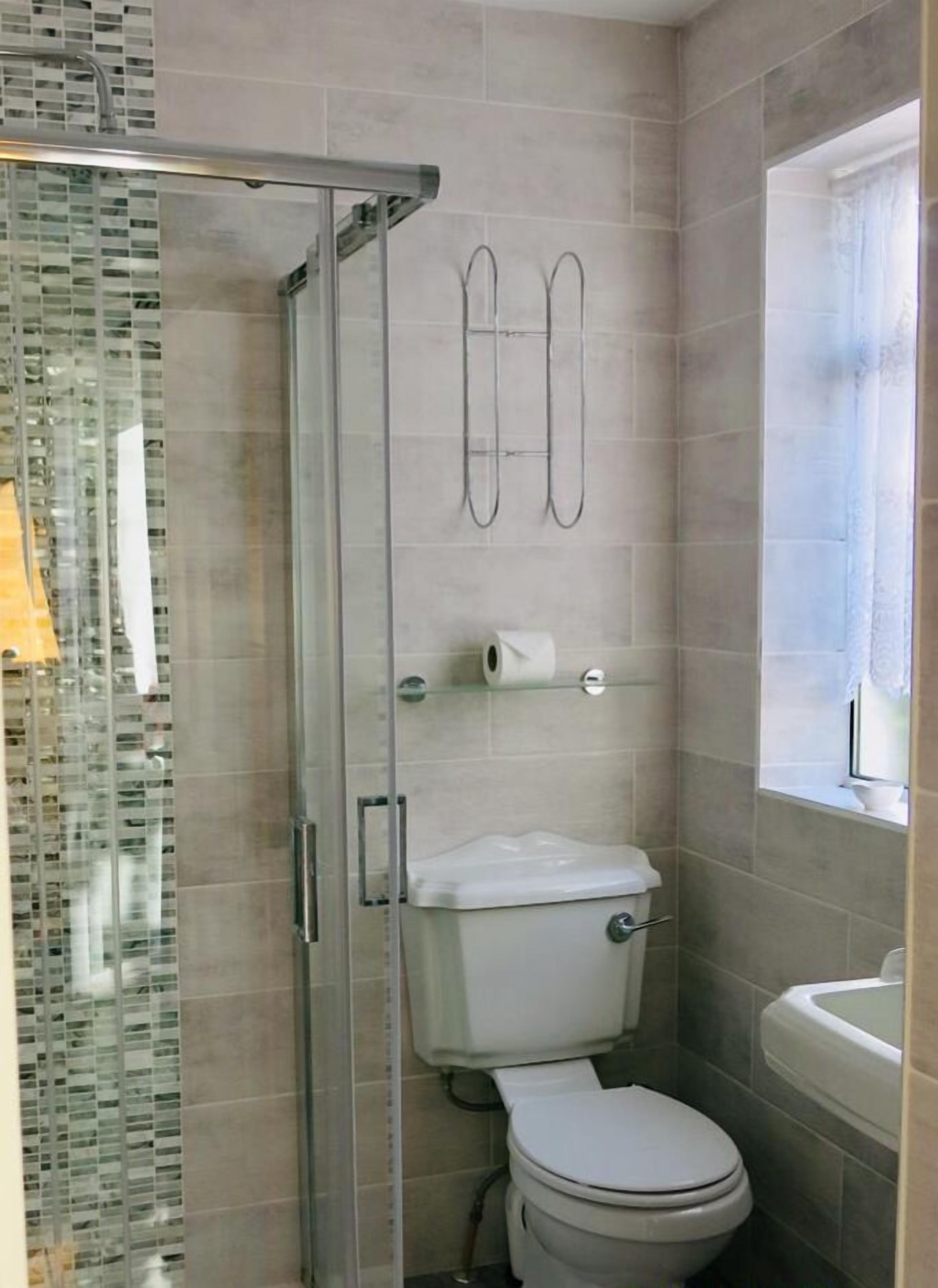 Une salle de bain avec une douche à parois de verre, des toilettes et un lavabo.