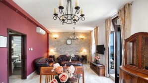 Una sala de estar con pared de piedra, un candelabro, un sofá y una mesa de centro de madera con un jarrón de flores.