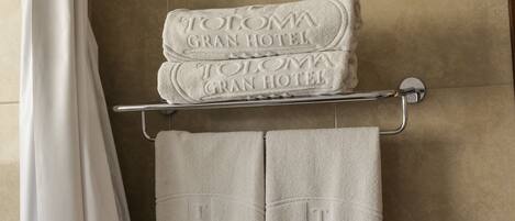 A bathroom with a shower curtain, a towel rack holding two folded towels, and a towel rack with two towels.